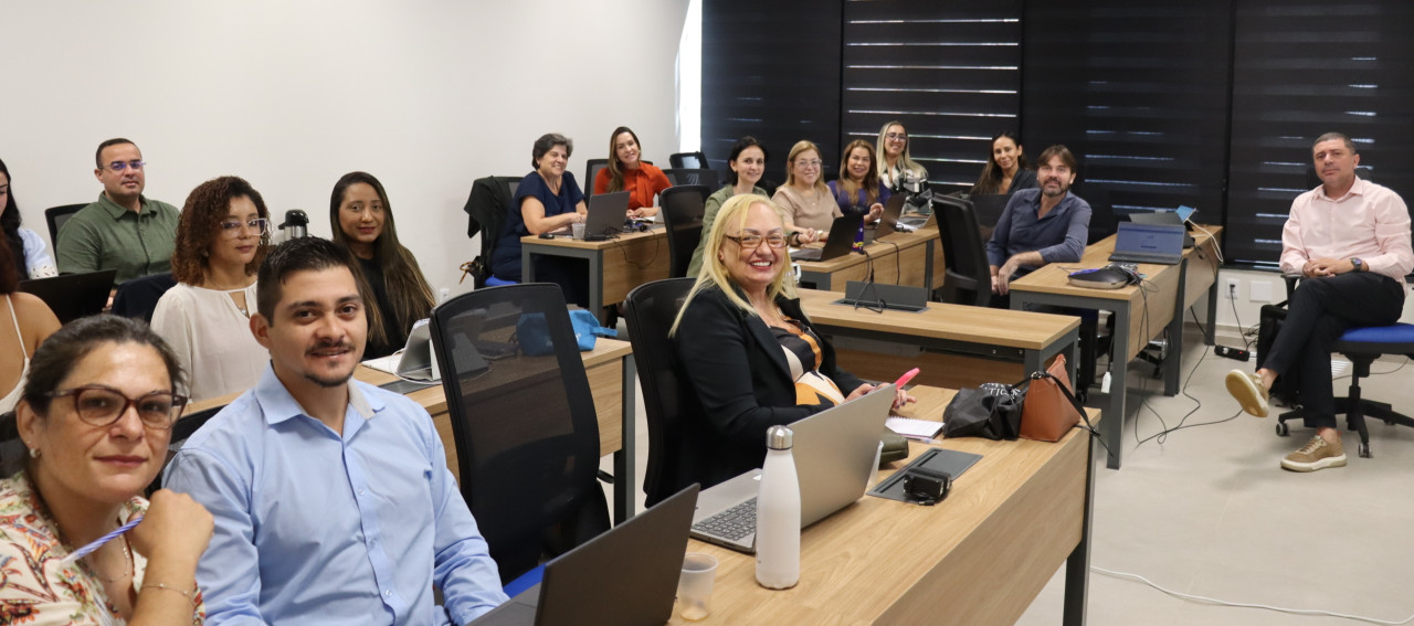 Um grupo de pessoas em uma sala com mesas participando de um treinamento