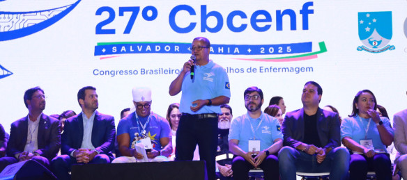 Pessoa em pé no palco de um auditório falando para o público