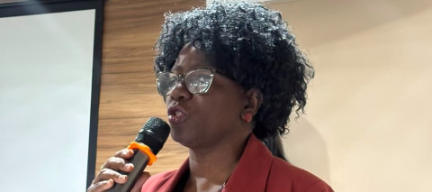 Pessoa em pé falando ao microfone